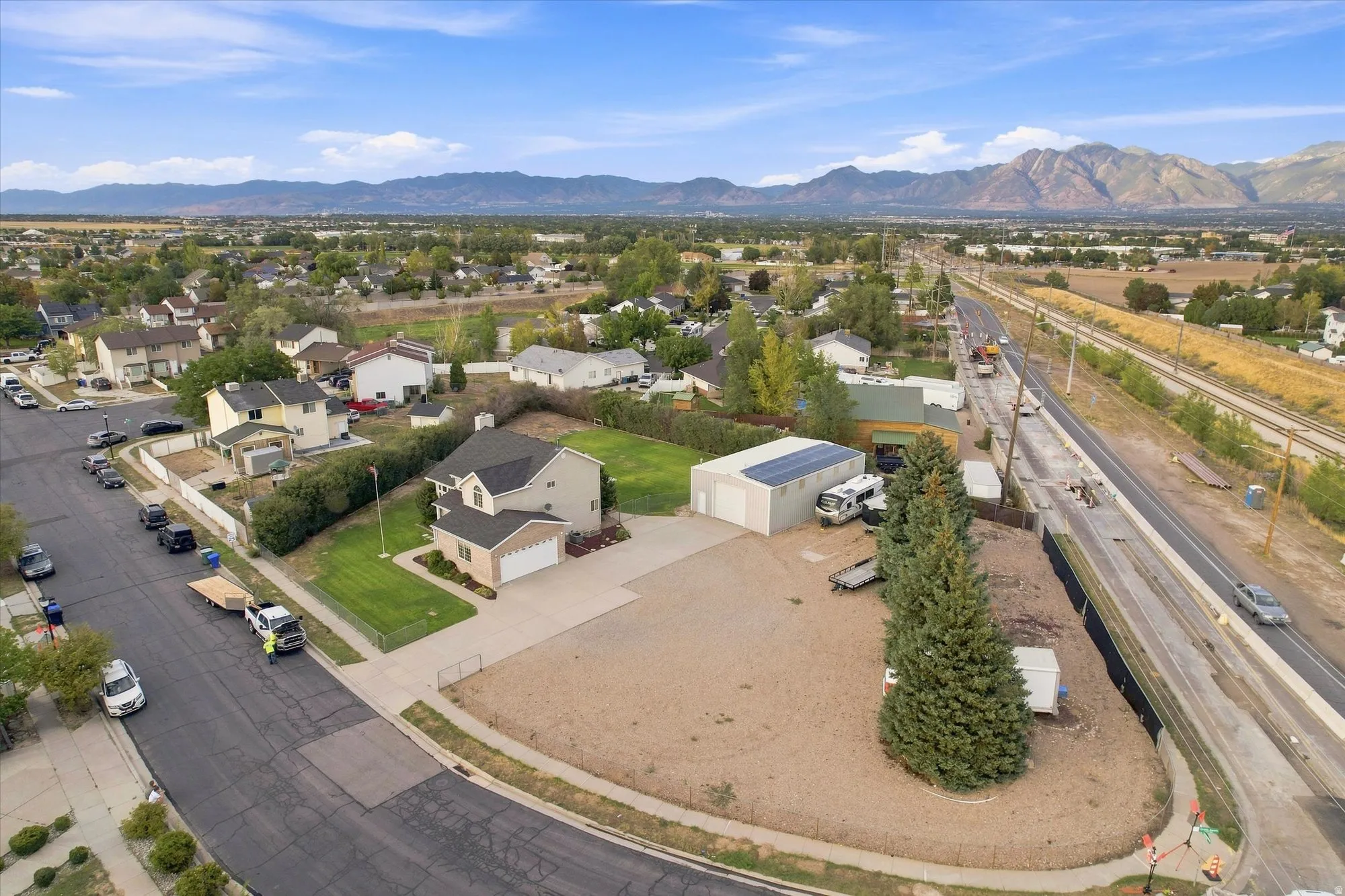 Single-family residence featuring an attached garage, a detached accessory building with rooftop solar panels, and a large gravel lot