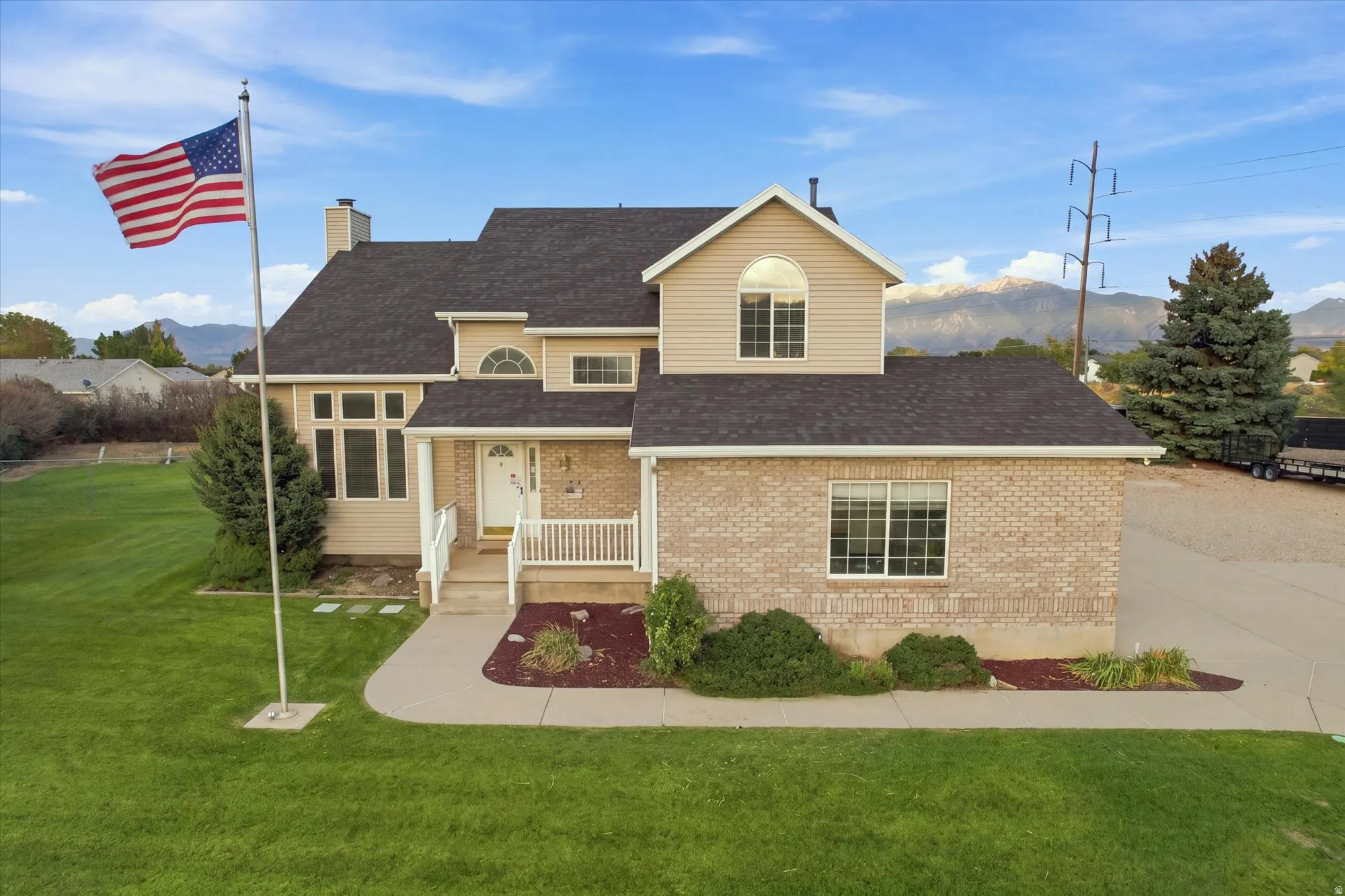 Exterior featuring brick and siding finishes, a covered front porch with white railing, a dark shingle roof, and a mature lawn