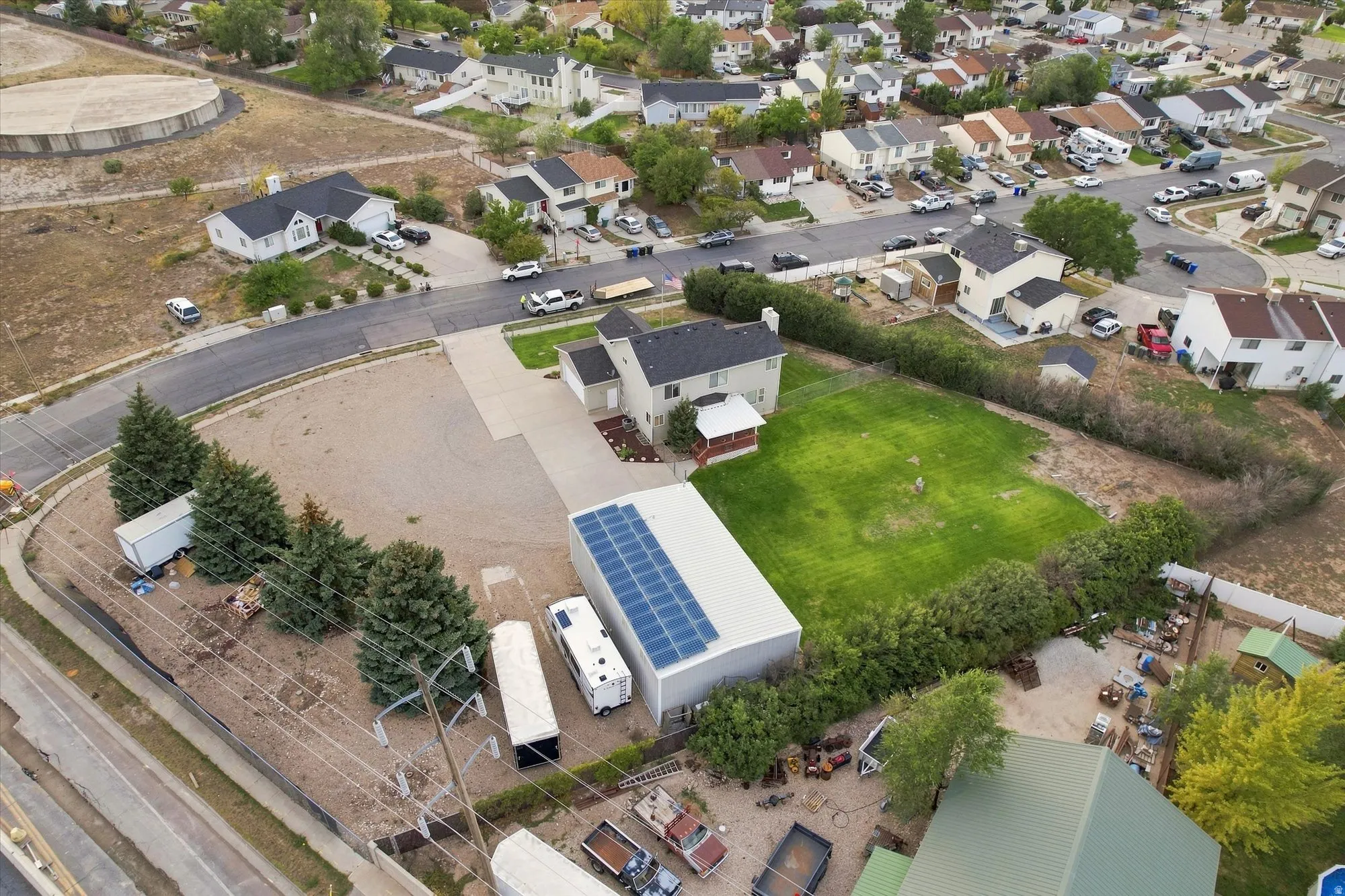 Expansive property featuring a large detached outbuilding with solar panels, a substantial grass area, and mature perimeter hedging