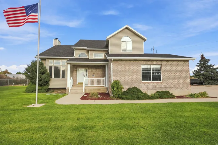 Brick facade with siding accents, covered front porch, large front windows, and landscaped shrubbery