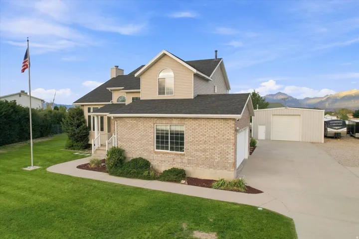 Traditional-style residence with brick and siding exterior, multi-car garage, and an additional metal outbuilding