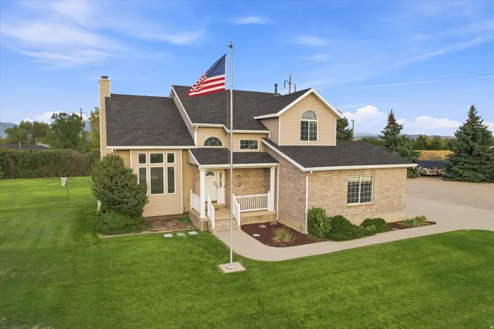 Two-story residence featuring a brick and siding exterior, front porch with white railing, and a flag pole