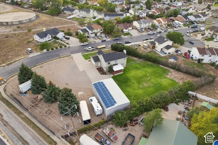 Expansive property featuring a large detached outbuilding with solar panels, a substantial grass area, and mature perimeter hedging