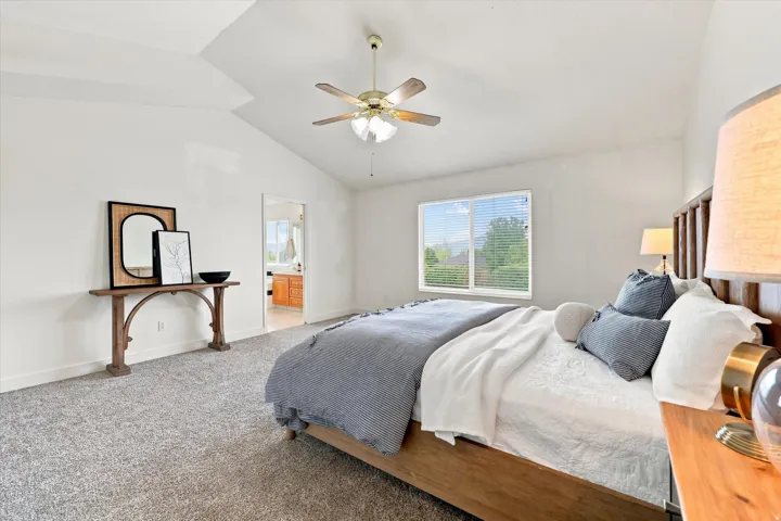 Vaulted ceiling with a ceiling fan, light-toned carpet, and a window with horizontal blinds