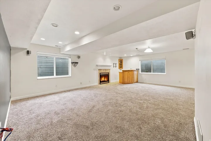 Recessed lighting, wood-finish wet bar, built-in cabinetry, fireplace with mantel, and carpeted flooring