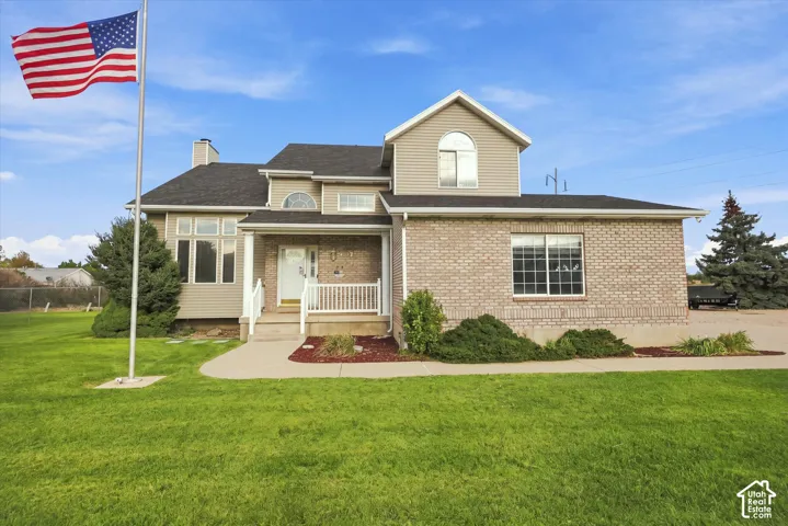 Brick facade with siding accents, covered front porch, large front windows, and landscaped shrubbery