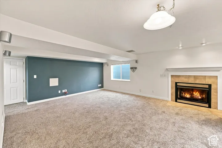 Recessed lighting, ceiling-mounted light fixture, fireplace with tile surround, white mantel, and carpeted flooring