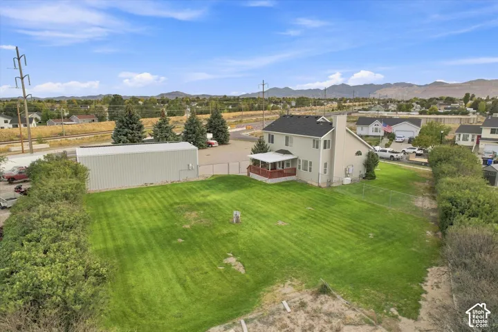 Expansive green lawn with a large detached metal structure and a two-story residence featuring an outdoor deck