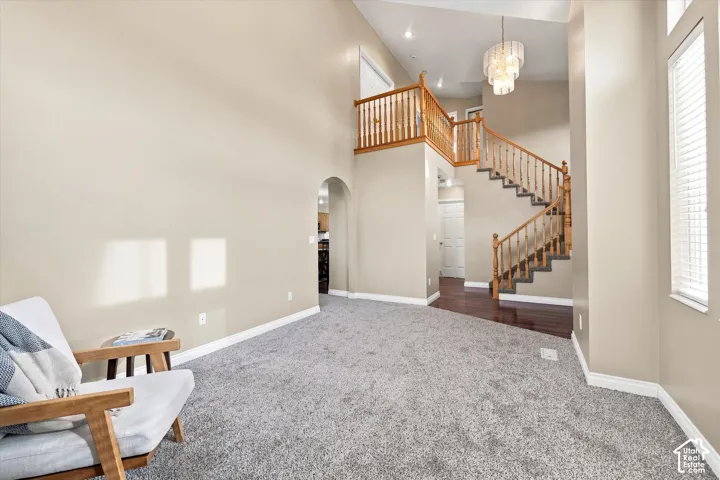 Vaulted ceilings, wood-finish staircase with balusters, upper landing, contemporary chandelier, and arched doorway