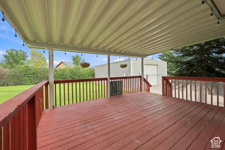 Expansive covered deck with red-stained wood flooring and railing, offering an outdoor living space