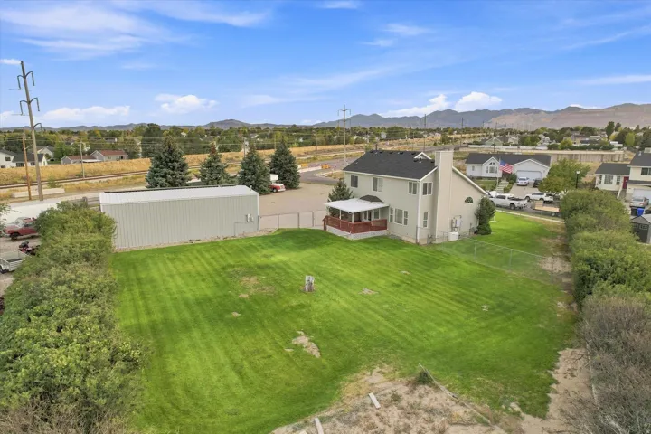 Expansive green lawn with a large detached metal structure and a two-story residence featuring an outdoor deck