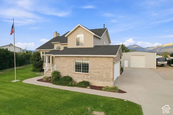 Traditional-style residence with brick and siding exterior, multi-car garage, and an additional metal outbuilding
