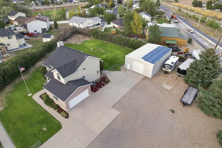 Two-story residence with attached two-car garage, expansive concrete driveway, and separate metal outbuilding with solar panels