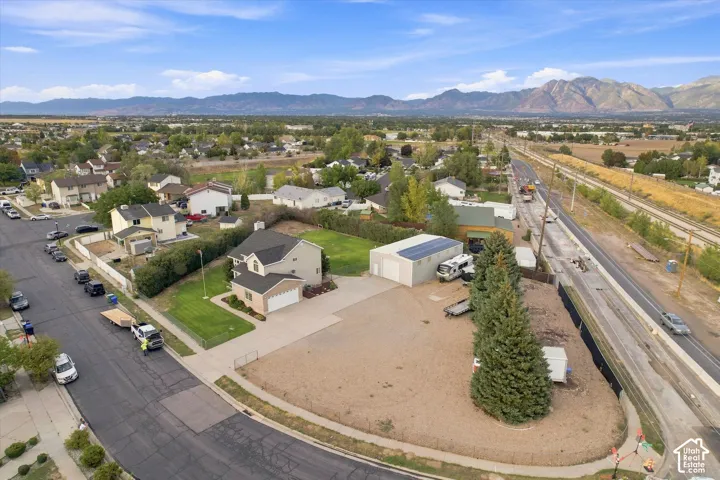 Single-family residence featuring an attached garage, a detached accessory building with rooftop solar panels, and a large gravel lot