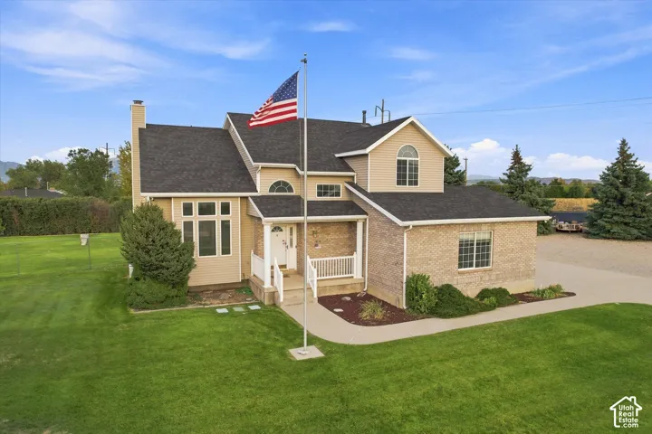 Two-story residence featuring a brick and siding exterior, front porch with white railing, and a flag pole