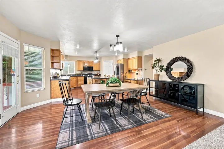 Open-concept dining area with wood-finish flooring, recessed lighting, and a modern chandelier