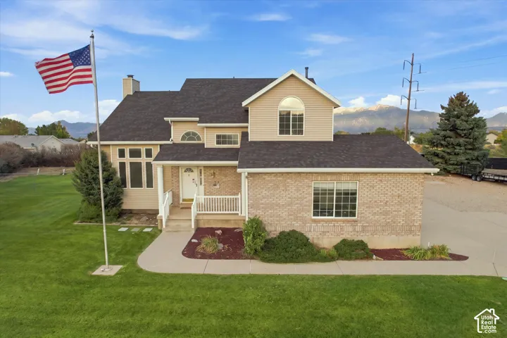 Exterior featuring brick and siding finishes, a covered front porch with white railing, a dark shingle roof, and a mature lawn