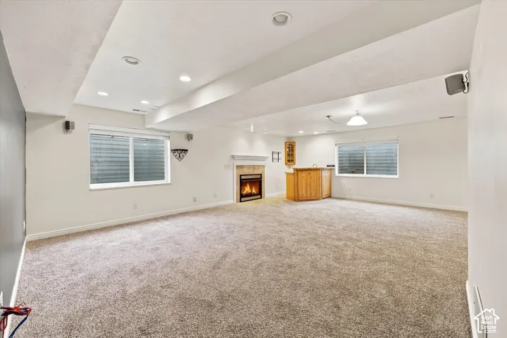 Recessed lighting, wood-finish wet bar, built-in cabinetry, fireplace with mantel, and carpeted flooring
