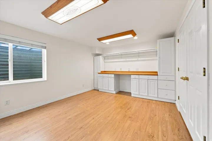 Wood-finish flooring, built-in white cabinetry, wood-finish countertop, recessed shelving, and a double-door closet