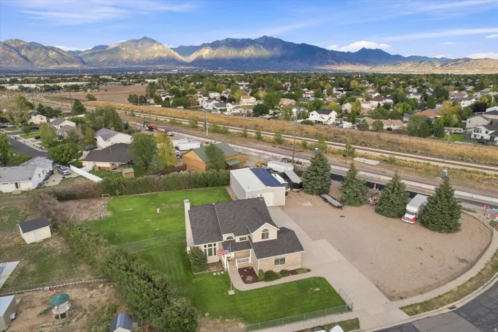 Expansive lot featuring a substantial gravel parking area, mature evergreen trees, and a two-story residence with a gabled roof