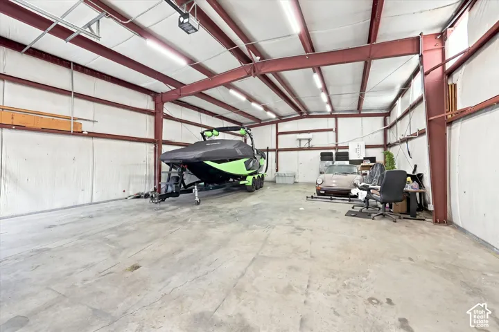 Spacious interior with exposed steel beam construction, corrugated wall panels, concrete flooring, and overhead lighting