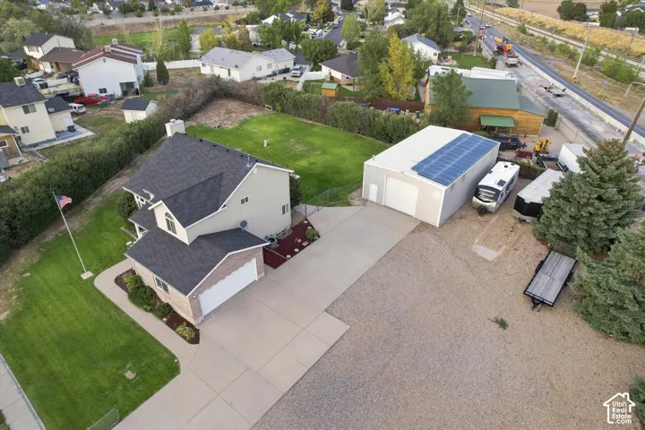 Two-story residence with attached two-car garage, expansive concrete driveway, and separate metal outbuilding with solar panels