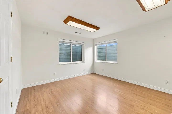 Wood-finish flooring, white walls, two windows with blinds, and recessed lighting