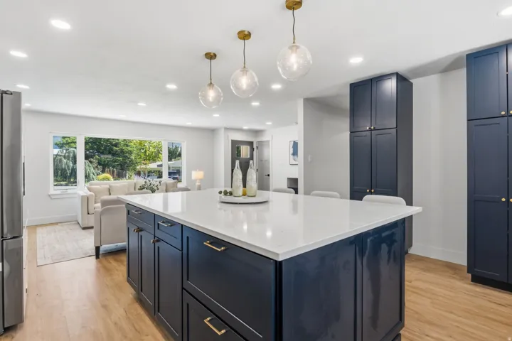 Expansive kitchen island with a light-toned countertop, deep blue cabinetry, and gold-toned hardware