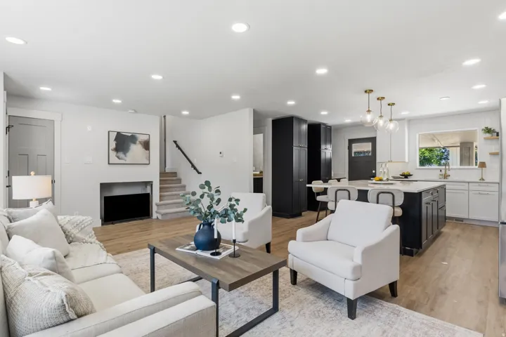 Open-concept living space featuring wood-finish flooring, recessed lighting, and a modern kitchen with an island and pendant lighting