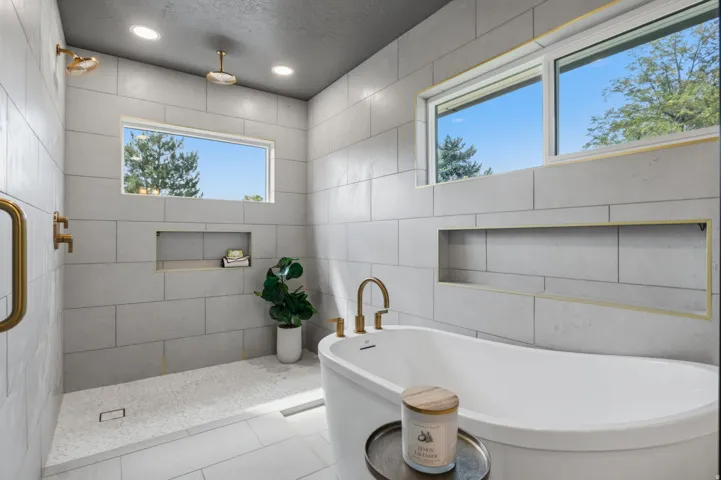 Primary walk in shower and freestanding tub with rain head and lighted wall niches.
