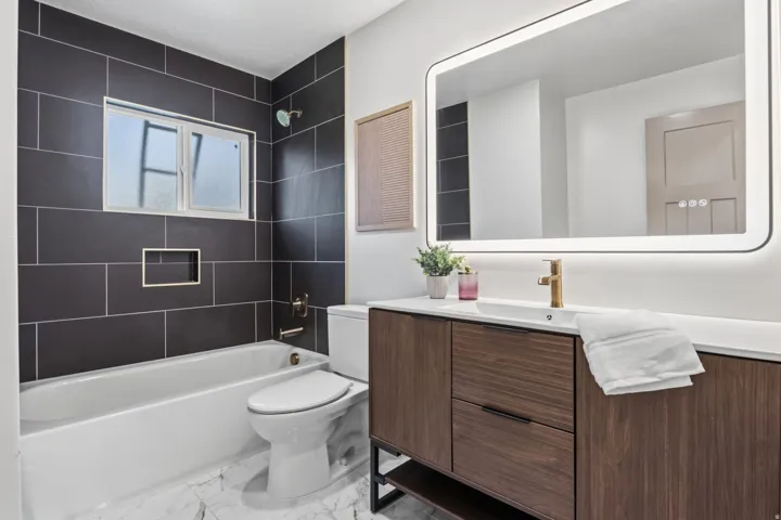 Modern vanity with wood-finish cabinetry, white countertop, and gold-tone faucet