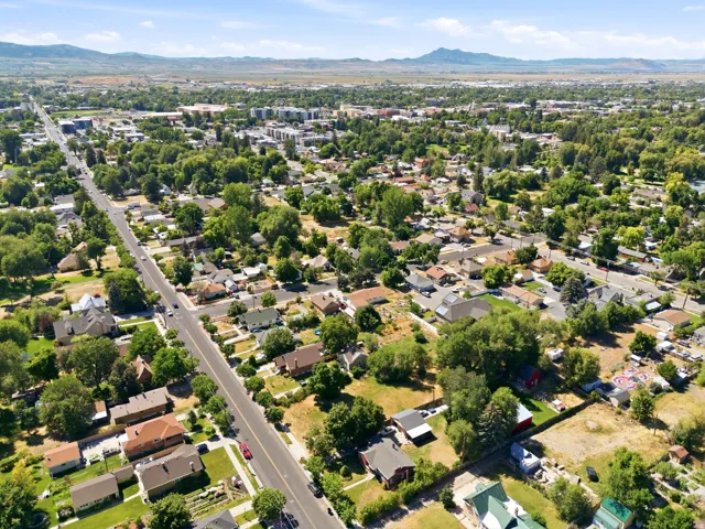 Expansive suburban landscape with varied architectural styles, mature tree coverage, and distant mountainous terrain under a clear sky