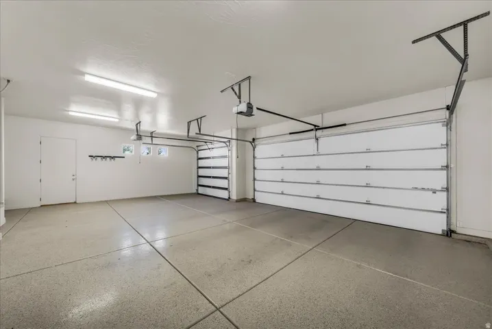 Spacious garage with an epoxy-coated concrete floor, two overhead garage doors, and three transom windows