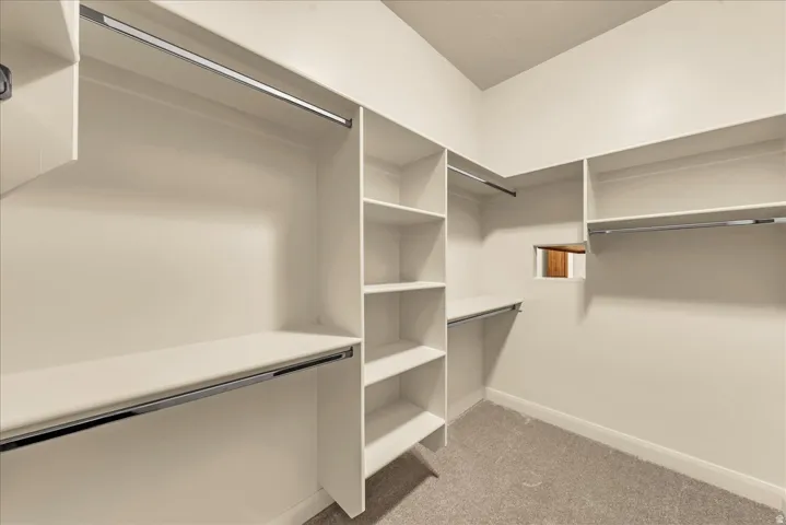 Built-in closet system with multiple shelving units, hanging rods, and a neutral carpeted floor
