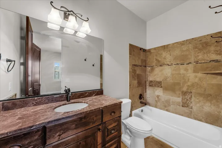 Vanity with wood-finish cabinetry, integrated sink, and stone countertop
