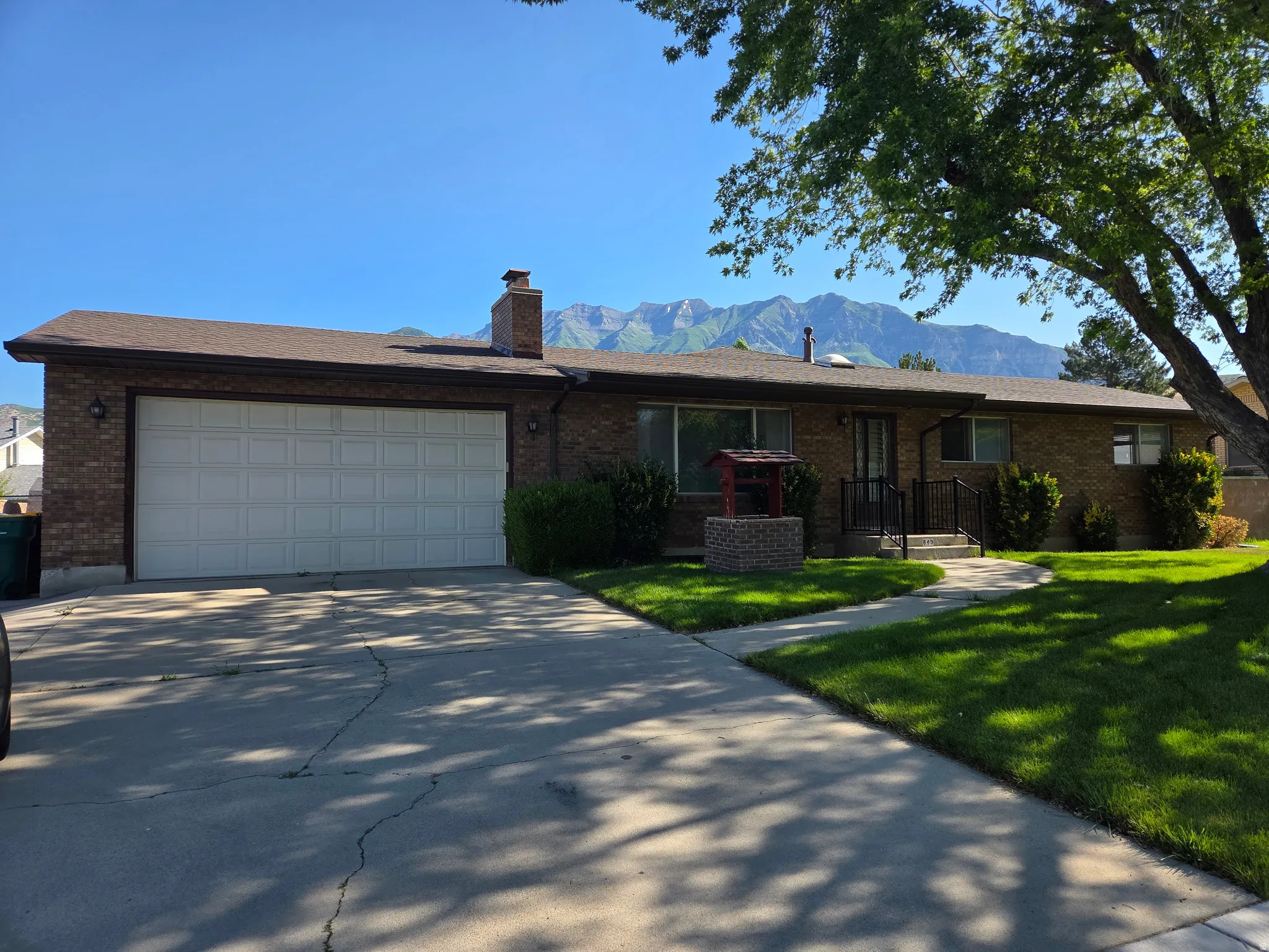 Brick exterior with attached two-car garage, concrete driveway, and front lawn