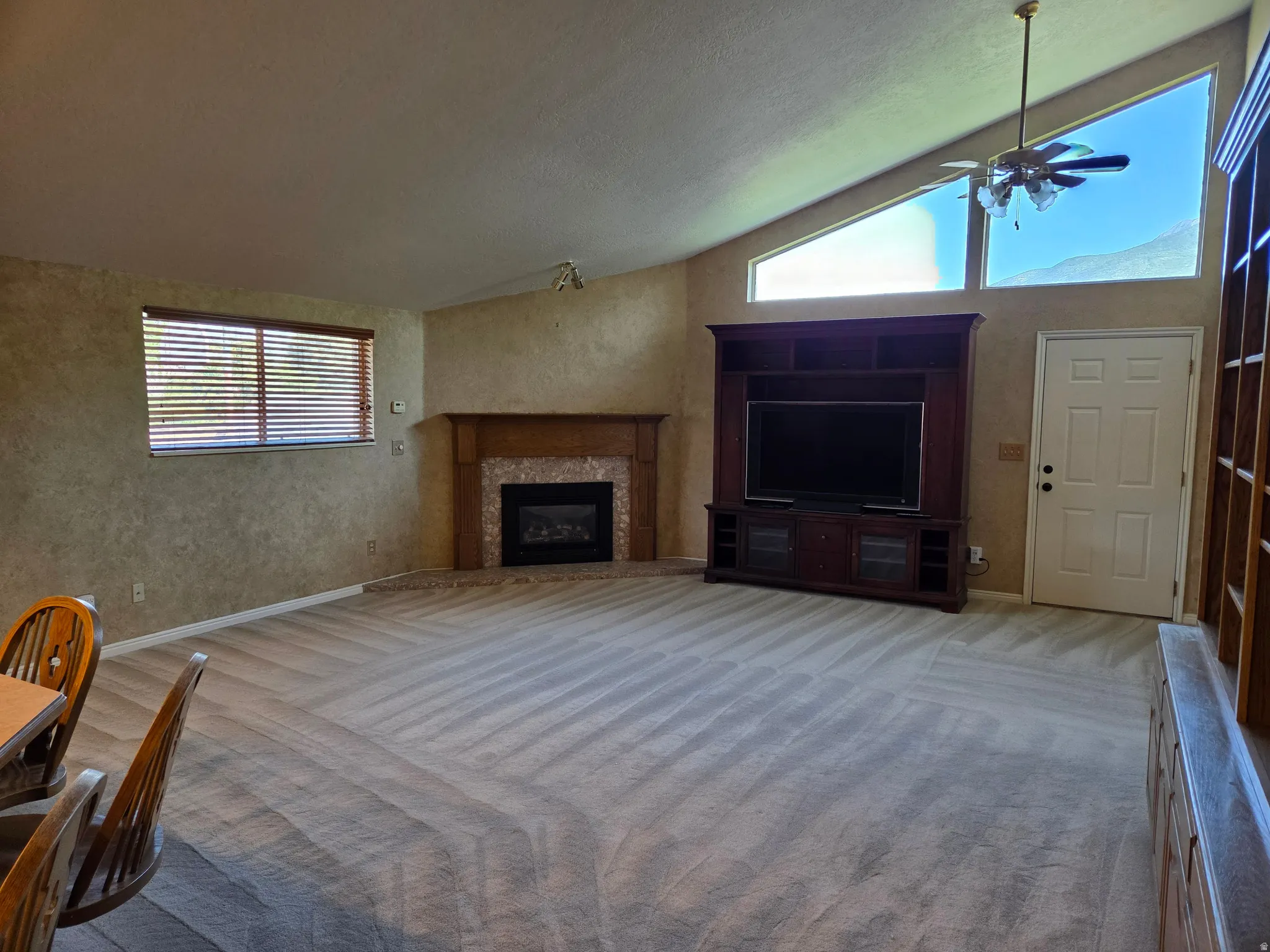 Vaulted ceilings, a built-in entertainment center, and a corner fireplace with a stone surround