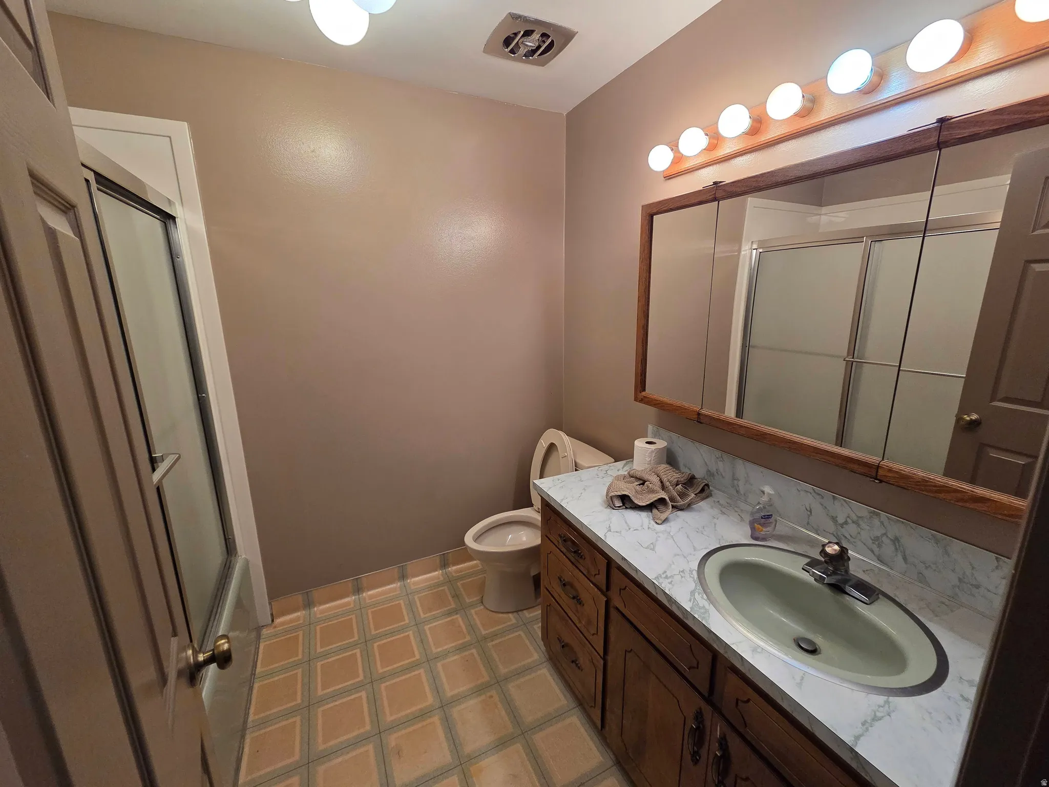 Bathroom featuring a full vanity with wood cabinetry, a built-in sink, and a mirrored medicine cabinet