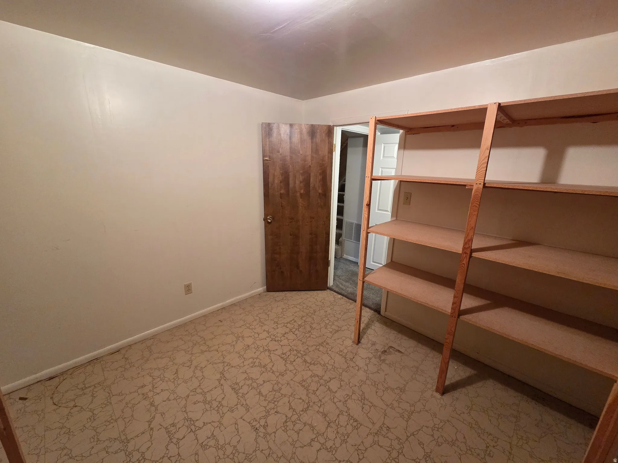 Built-in shelving unit providing ample storage, neutral wall paint, and wood-finish door