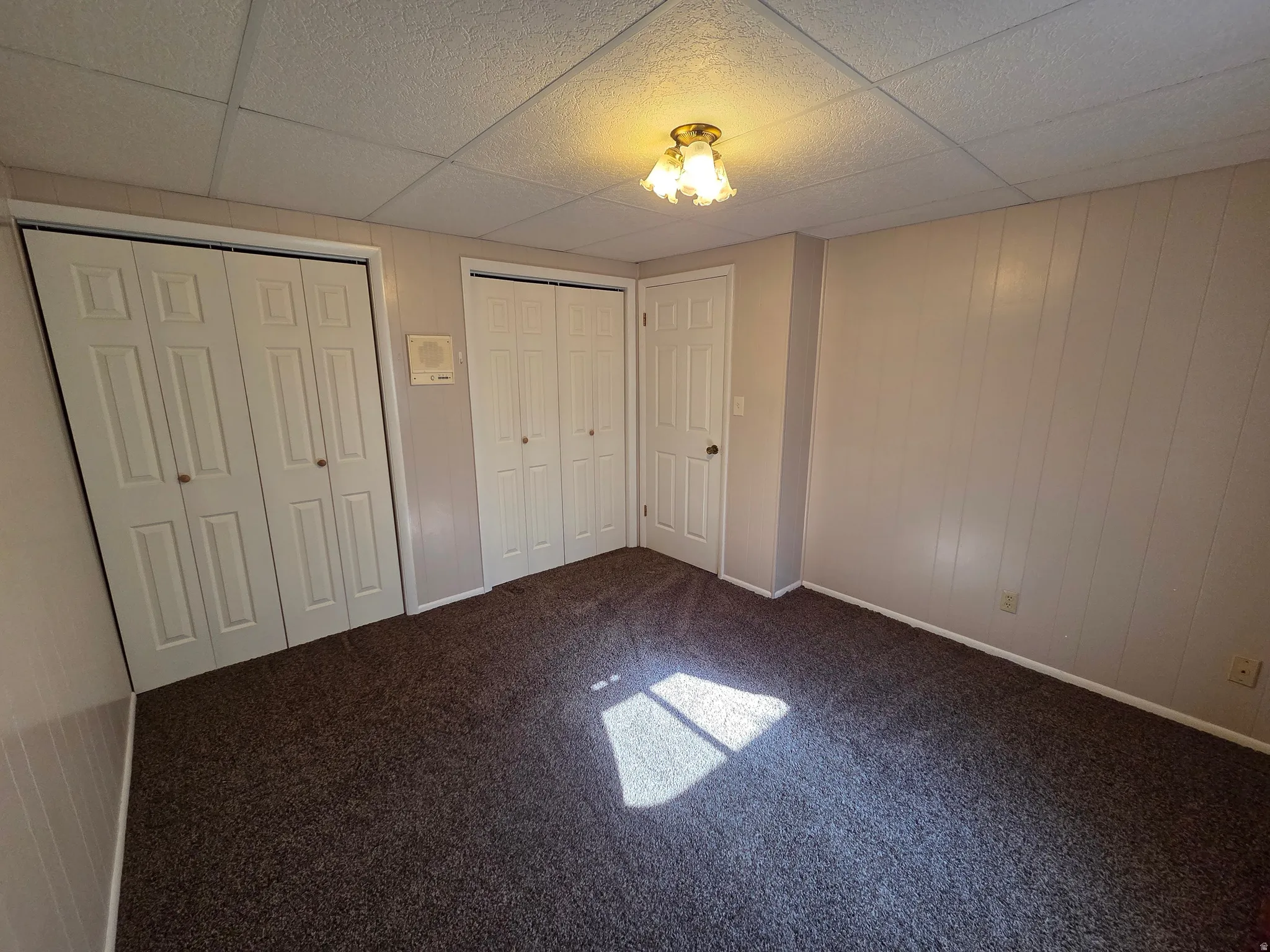 Wall-to-wall carpeting, two bifold closet doors, a single door, and a ceiling-mounted light fixture