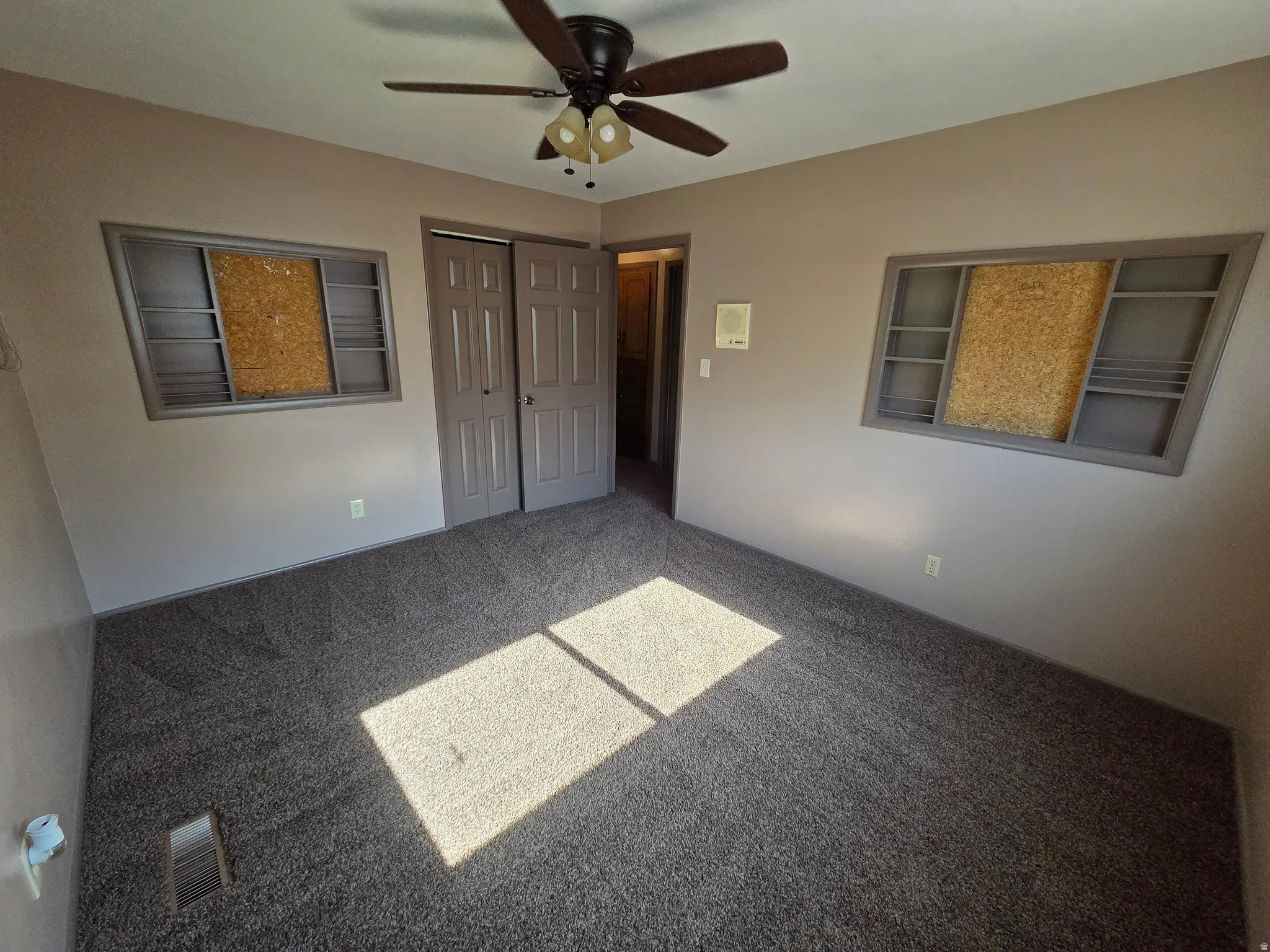 Textured carpet flooring, neutral wall paint, and a ceiling fan with integrated lighting