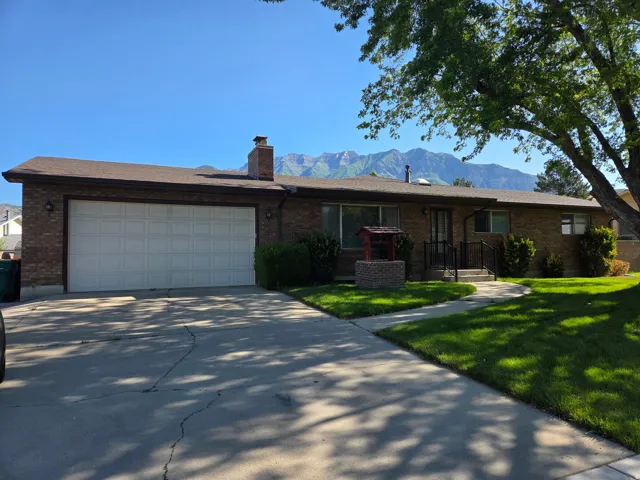 Brick exterior with attached two-car garage, concrete driveway, and front lawn