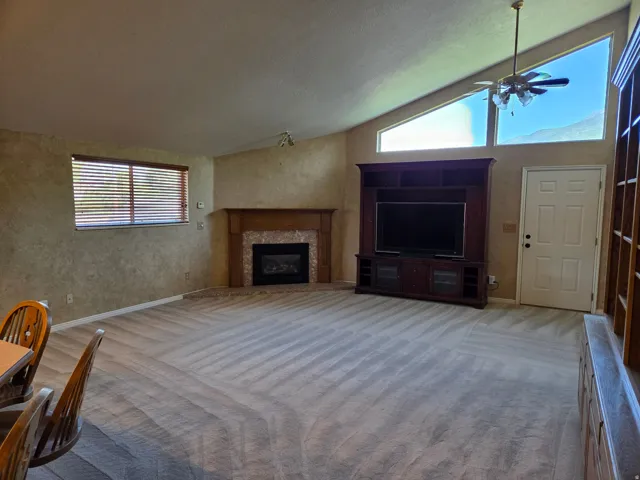 Vaulted ceilings, a built-in entertainment center, and a corner fireplace with a stone surround