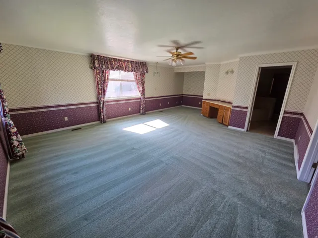 Master Bedroom. Spacious room featuring patterned wallpaper, a window with valance and drapes, and a ceiling fan