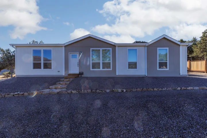 Contemporary exterior with mixed siding, multiple windows, and a stone-lined pathway leading to the entry