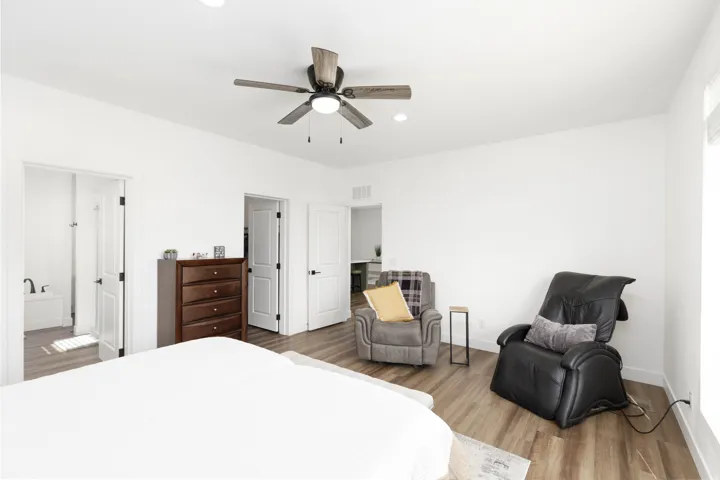 Wood-finish flooring, recessed lighting, ceiling fan with integrated light, and multiple doors with dark hardware