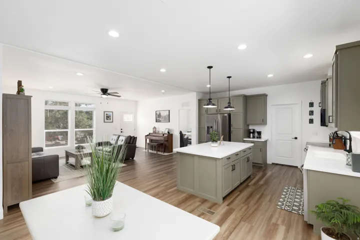 Kitchen island with white countertop, pendant lighting, wood-finish flooring, recessed lighting, and expansive windows