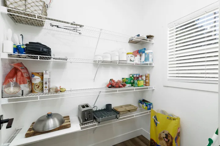 White wire shelving system, built-in window with horizontal blinds, and wood-finish flooring