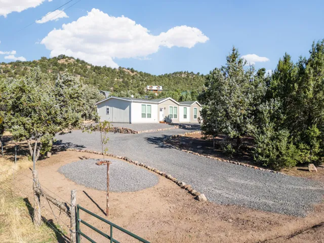 Gravel driveway leading to a light-colored exterior with multiple windows