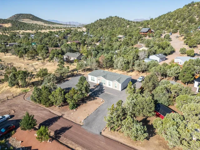 Single-story residence set on a large lot with a gravel driveway, surrounded by mature trees and natural landscaping